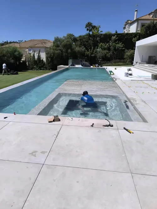 Buzo inspeccionando una piscina de obra junto a un jardín