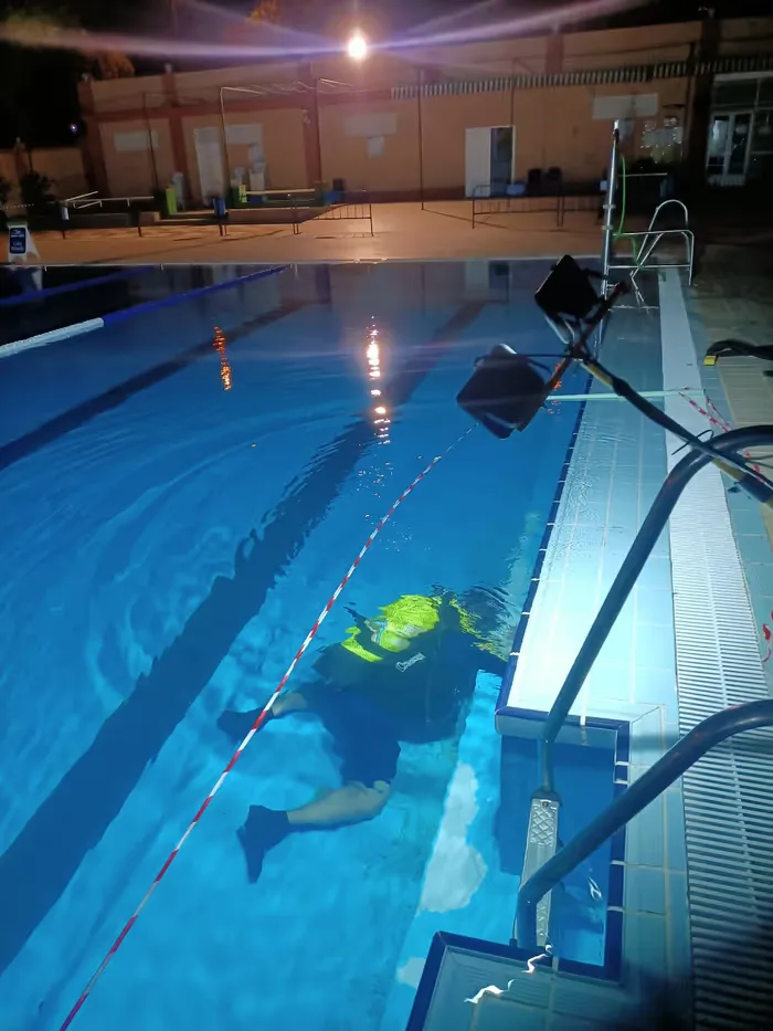 Buzo revisando el fondo iluminado de una piscina