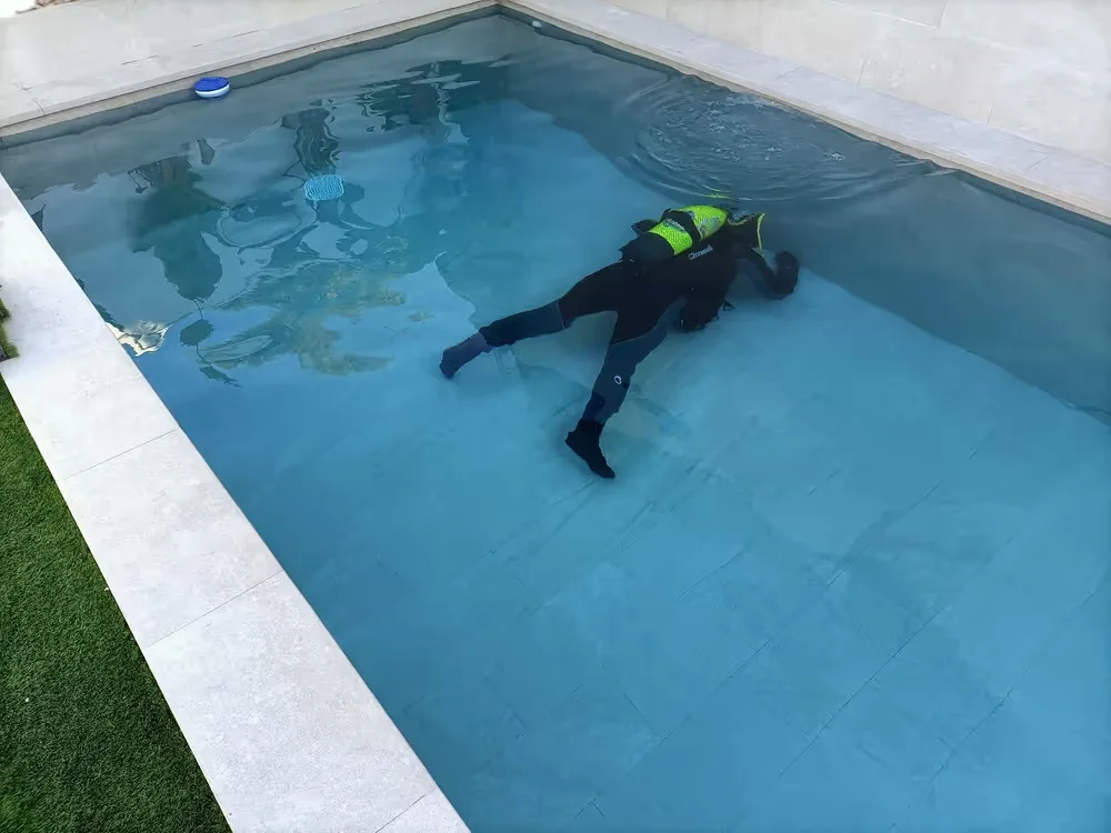 Buzo inspeccionando el vaso de una piscina llena en busca de fugas